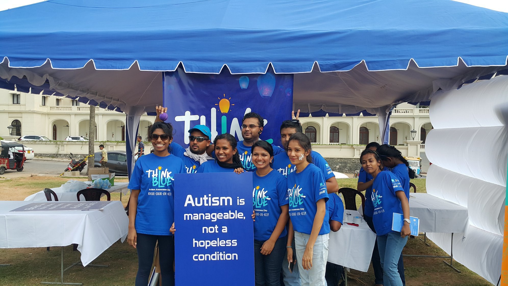 Photograph depicts members of the CAFS team from a past Autism Awareness Campaign. All are wearing blue t-shirts and they hold a big blue sign reading "Autism is manageable, not a hopeless condition"