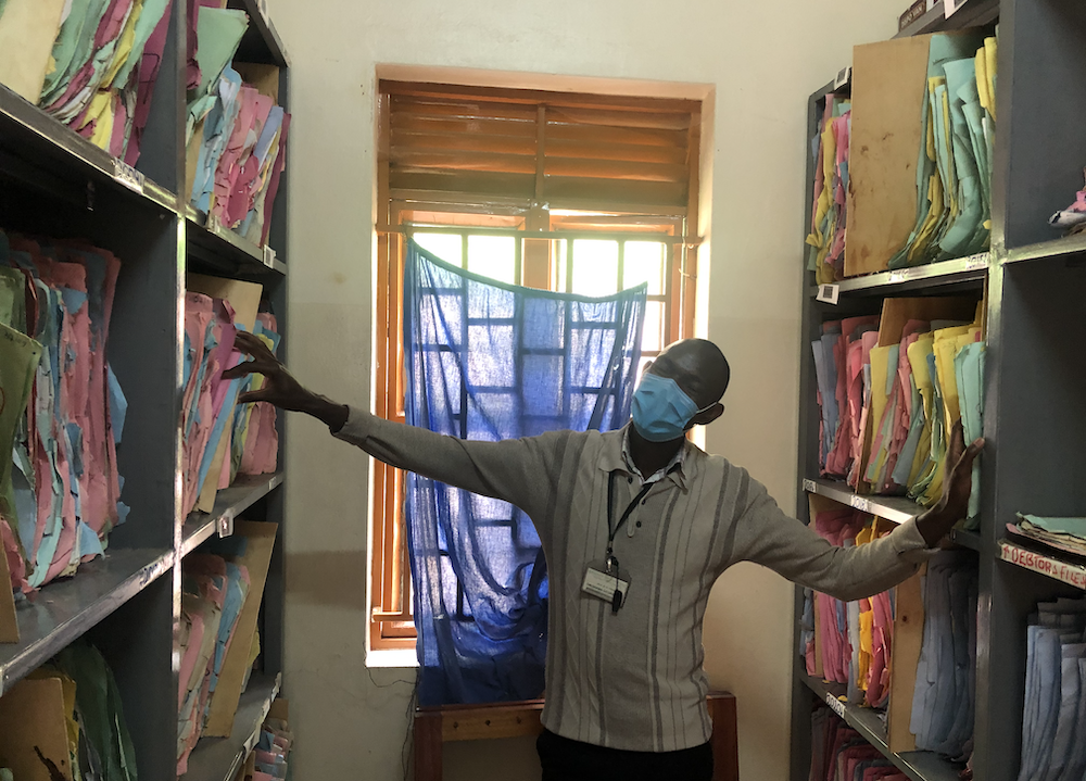 Kisiizi team member looks at shelves of folders in an administrative room at the hospital