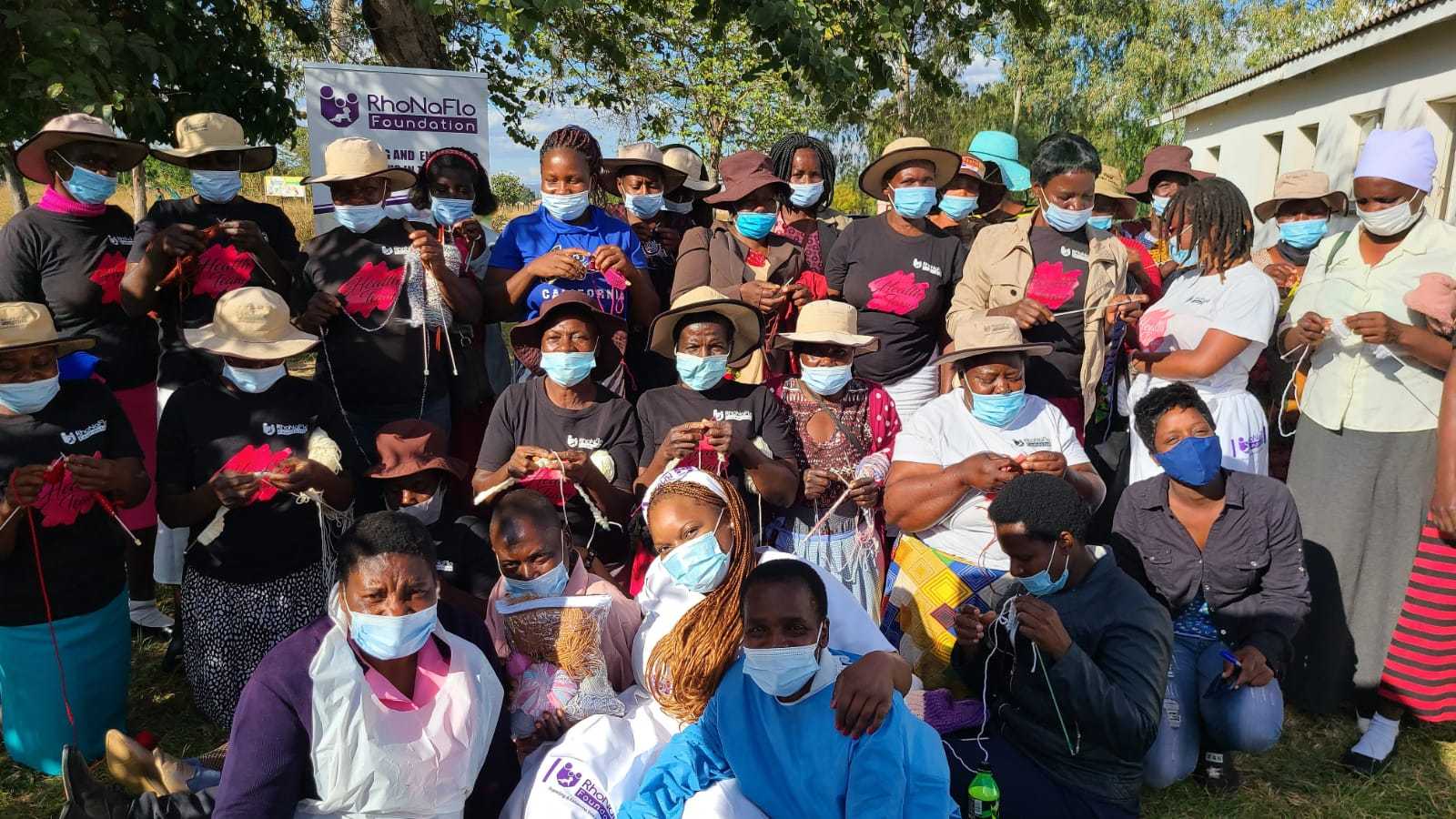 Large group of black women wearing face masks, gathered and smiling at the camera